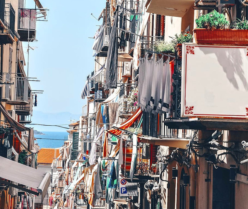 Colorful Naples street with laundry and sea view in the background