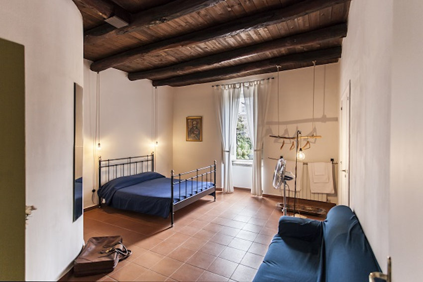 Family Suite — main bedroom with blue iron bed, sheer curtains and garden view at The Church B&B Naples